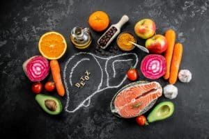 Fresh vegetables, fruits, and healthy fats surrounding a chalk outline of a stomach with the word "detox" written inside, emphasizing detox diet, gut health, and nutrition.