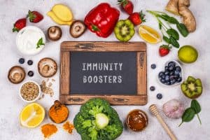 Fresh fruits and vegetables surrounding a chalkboard with "Immunity Boosters" written on it, promoting healthy lifestyle tips from Dr. Rachel West.